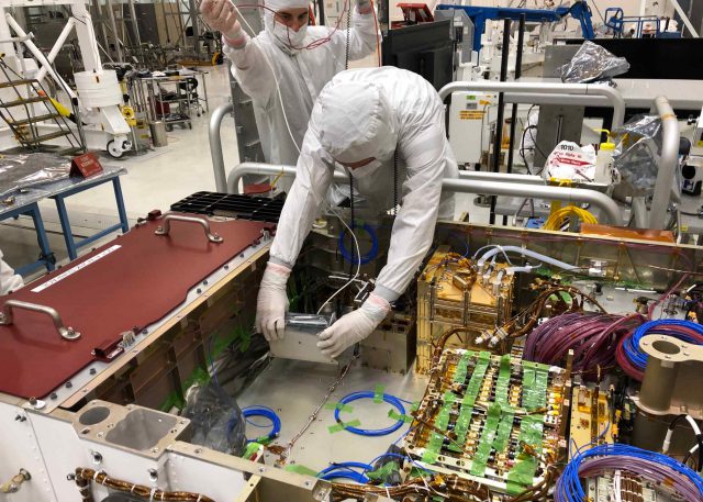 Technicians installing the Mastcam-Z Digital Electronics Assembly (DEA) into the body of the Mars 2020 mission’s Perseverance rover at JPL in April, 2019.
