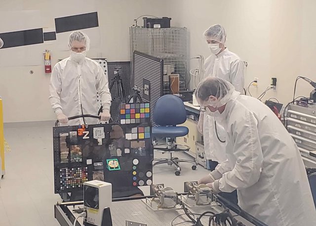 Members of the Mars 2020 Perseverance rover Mastcam-Z calibration group in the clean room setting up the “GeoBoard” rock and standards target for imaging by the flight cameras at Malin Space Science Systems in May, 2019.